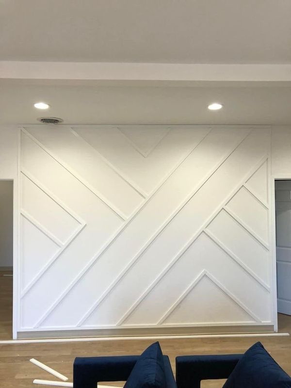 White accent wall with a large geometric batten pattern, above a low sofa