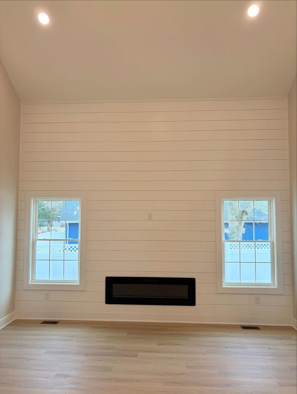 Full-height shiplap accent wall with a linear electric fireplace set between two windows