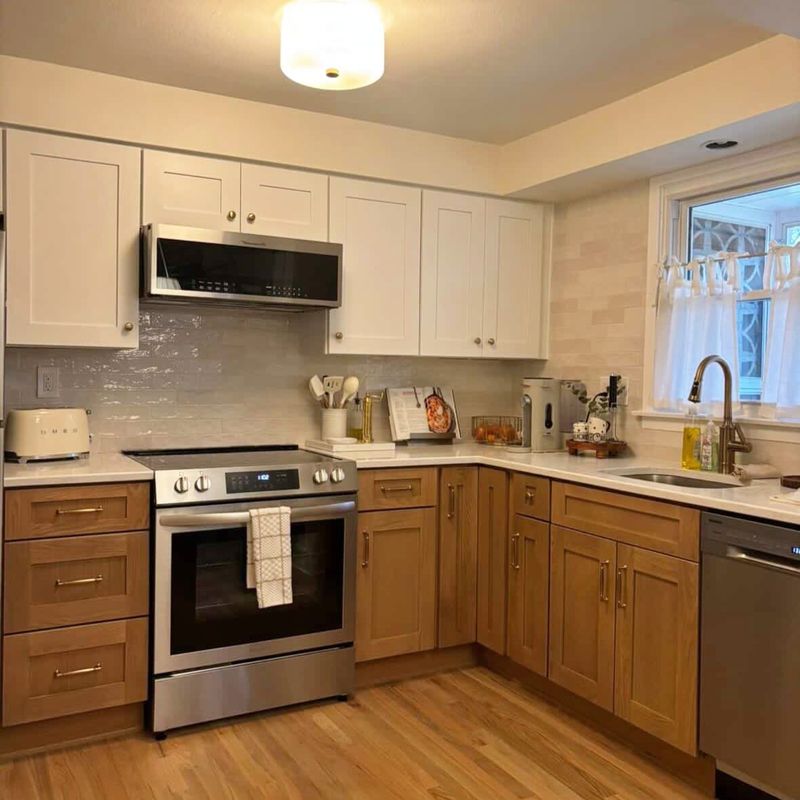 Two-tone kitchen with white upper cabinets, white oak base cabinets, quartz counters and brass fixtures